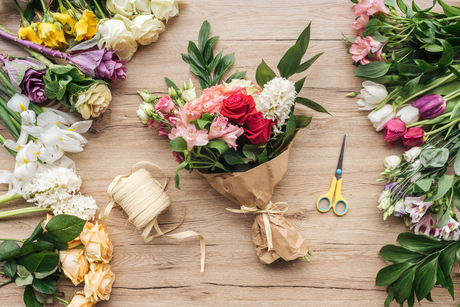 flower bouquet in paper wrapper and scissors on wooden surface.jpg